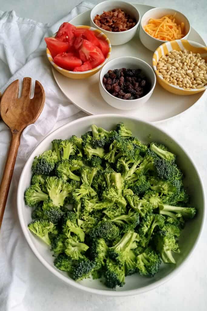 Low-carb broccoli salad next to a brown serving spoon and fresh ingredients.