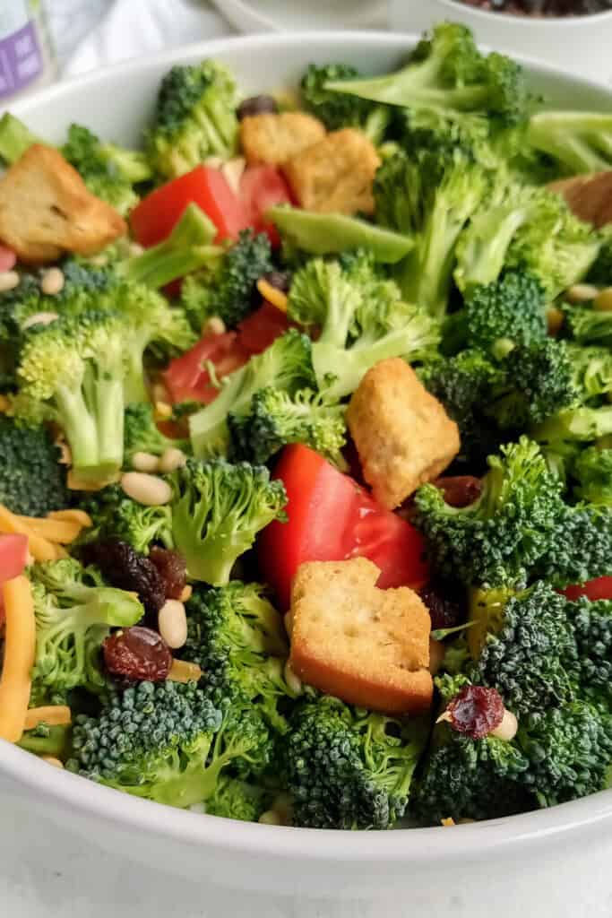 Broccoli salad inside a white serving bowl.