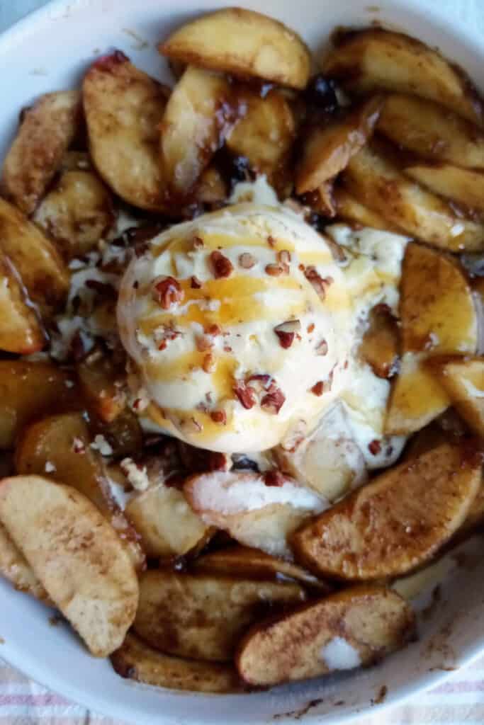 Baked brown sugar apples topped with vanilla ice cream, chopped walnuts, and caramel drizzle.