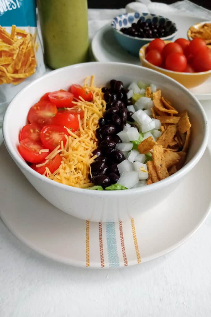 Taco salad with beans next to homemade avocado dressing.