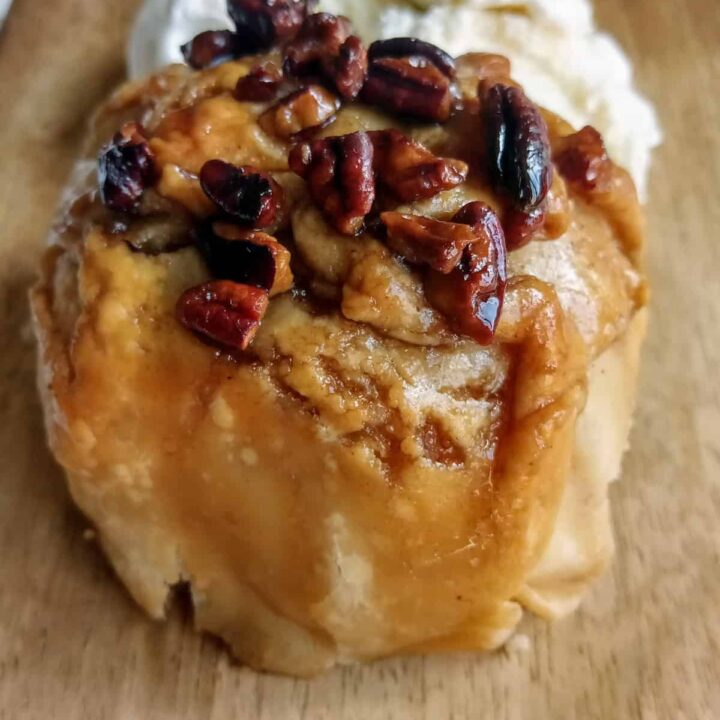 Old- fashioned apple dumpling next to a scoop of vanilla icecream.