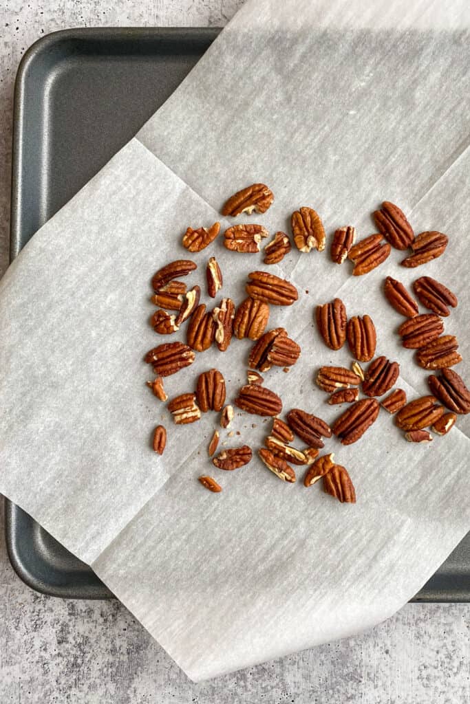 Toasted pecans on top of parchment paper.