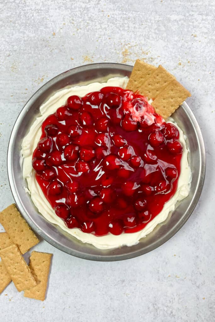 Overhead picture of cherry cheesecake dip with three graham crackers dipped in.