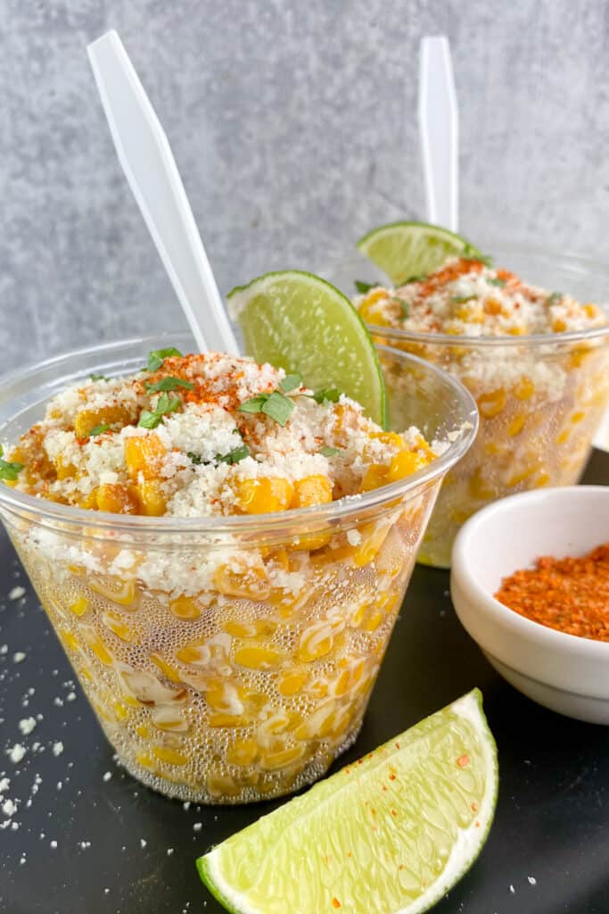 Mexican street corn in clear cups with spoons inside each cup of canned corn elote.