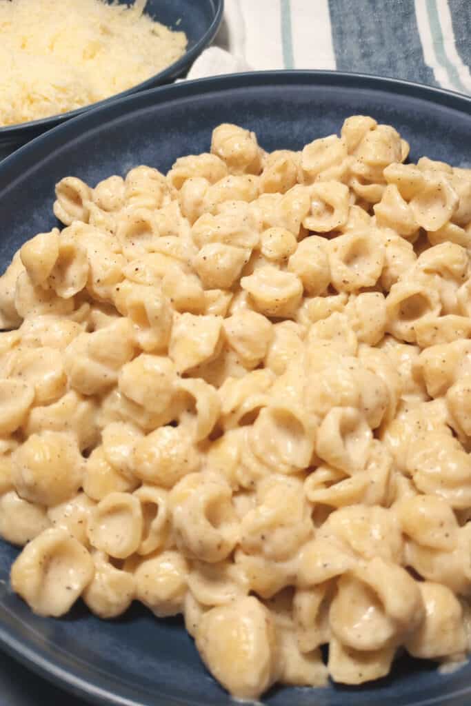 Mac and cheese in a blue bowl on a blue and white table cloth.