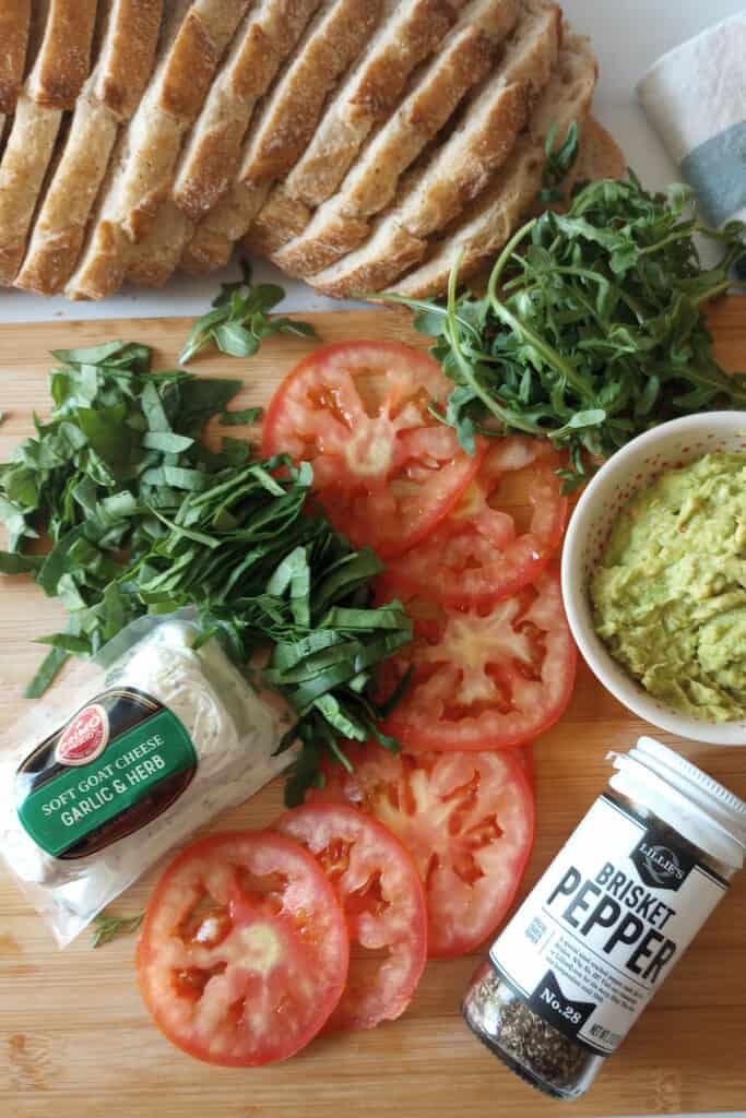 Spinach, arugula, thinly, sliced tomato, herb and garlic goat cheese, avocado, and sourdough bread.