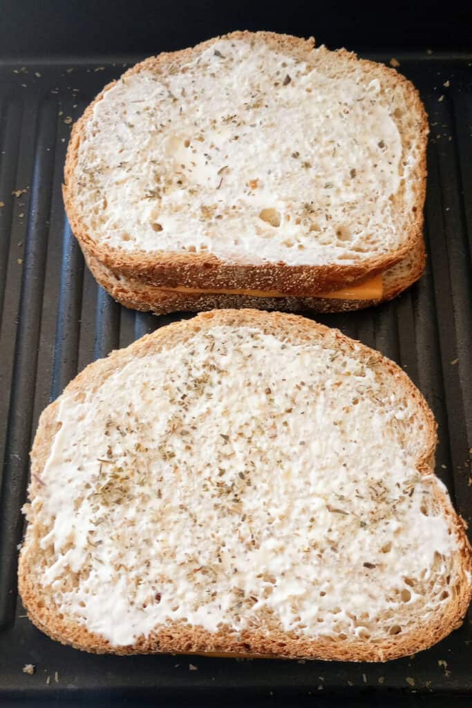 Mayo coated on bread and ready to be flipped in skillet. 