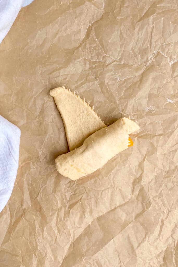 Rolling peaches in a crescent roll to make peach dumplings.