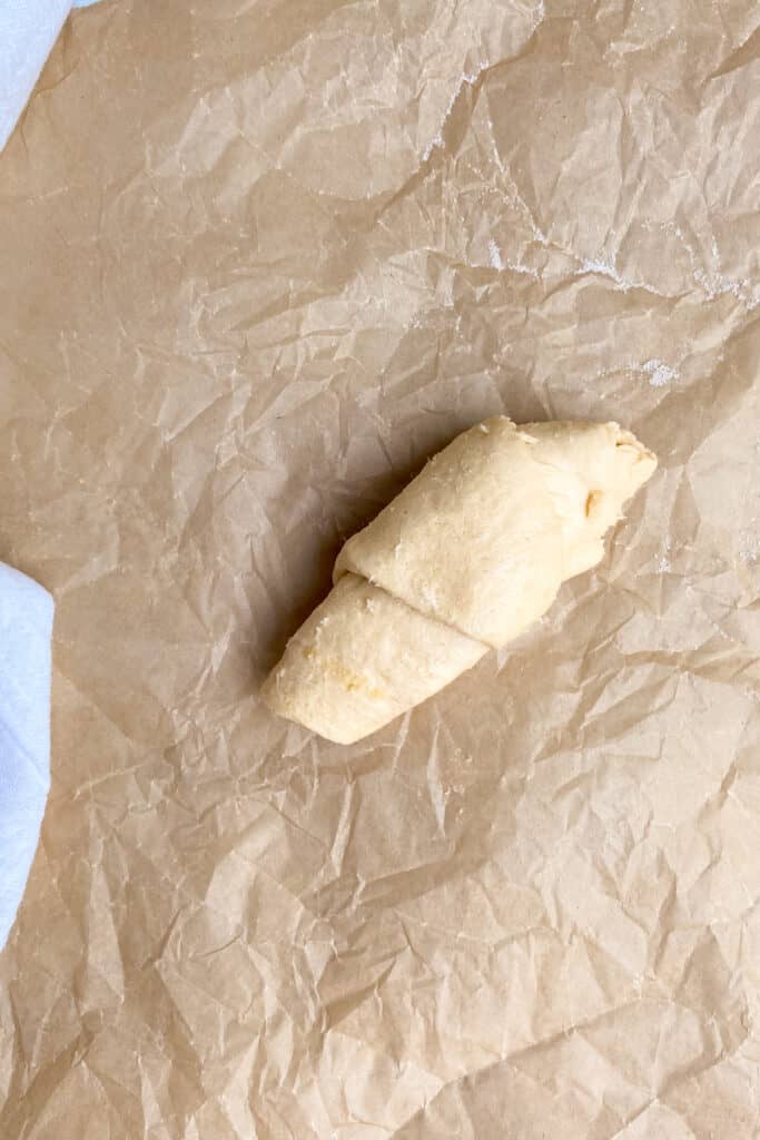 A crescent roll peach dumpling with edges sealed and ready for baking.