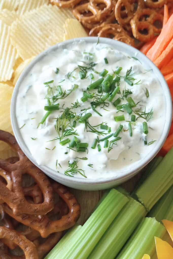 Bowl of dill pickle dip garnished with chopped dill and chives.