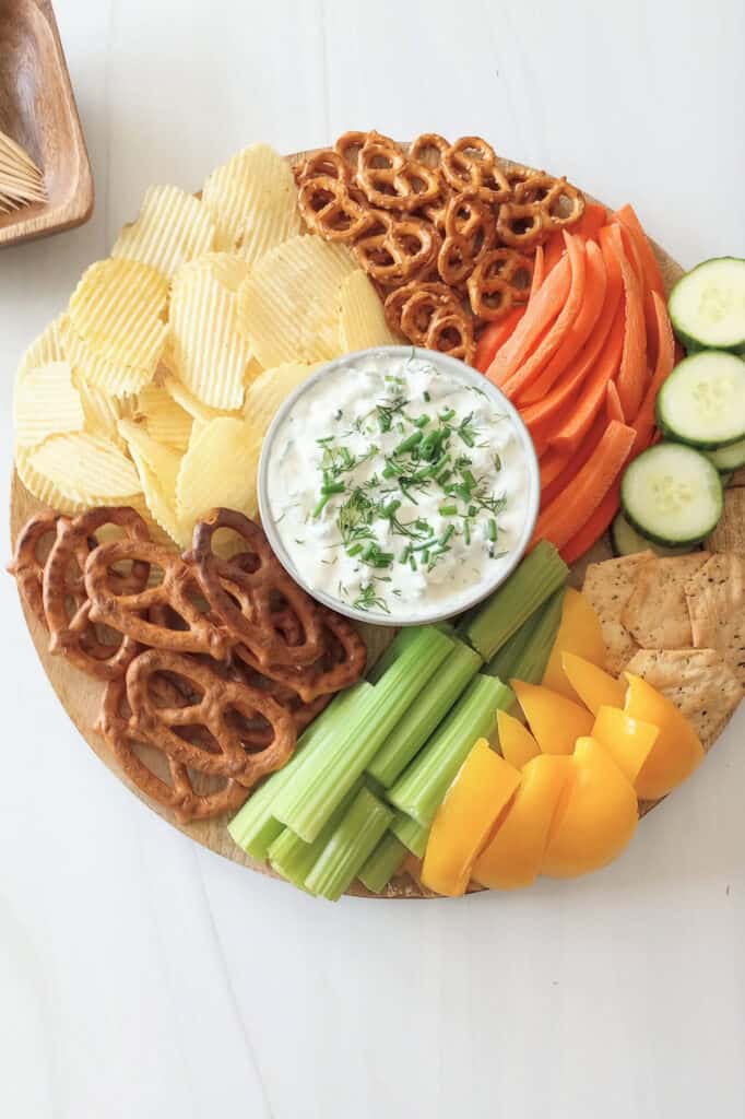 Dip on a serving platter with vegetables, chips, crackers, and pretzels.
