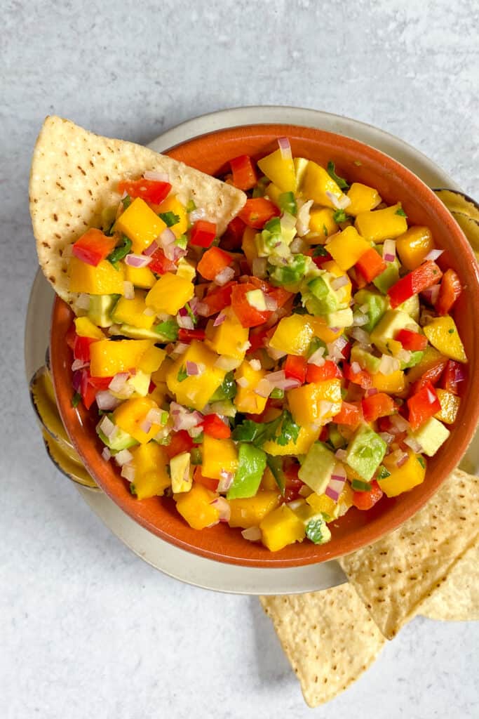 Bowl of mango salsa served as an appetizer with chips.