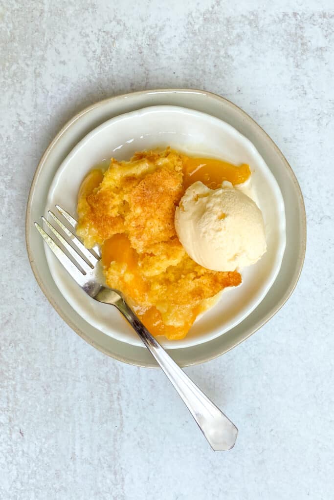 Peach Cobbler with Cake Mix served on a plate with ice cream.
