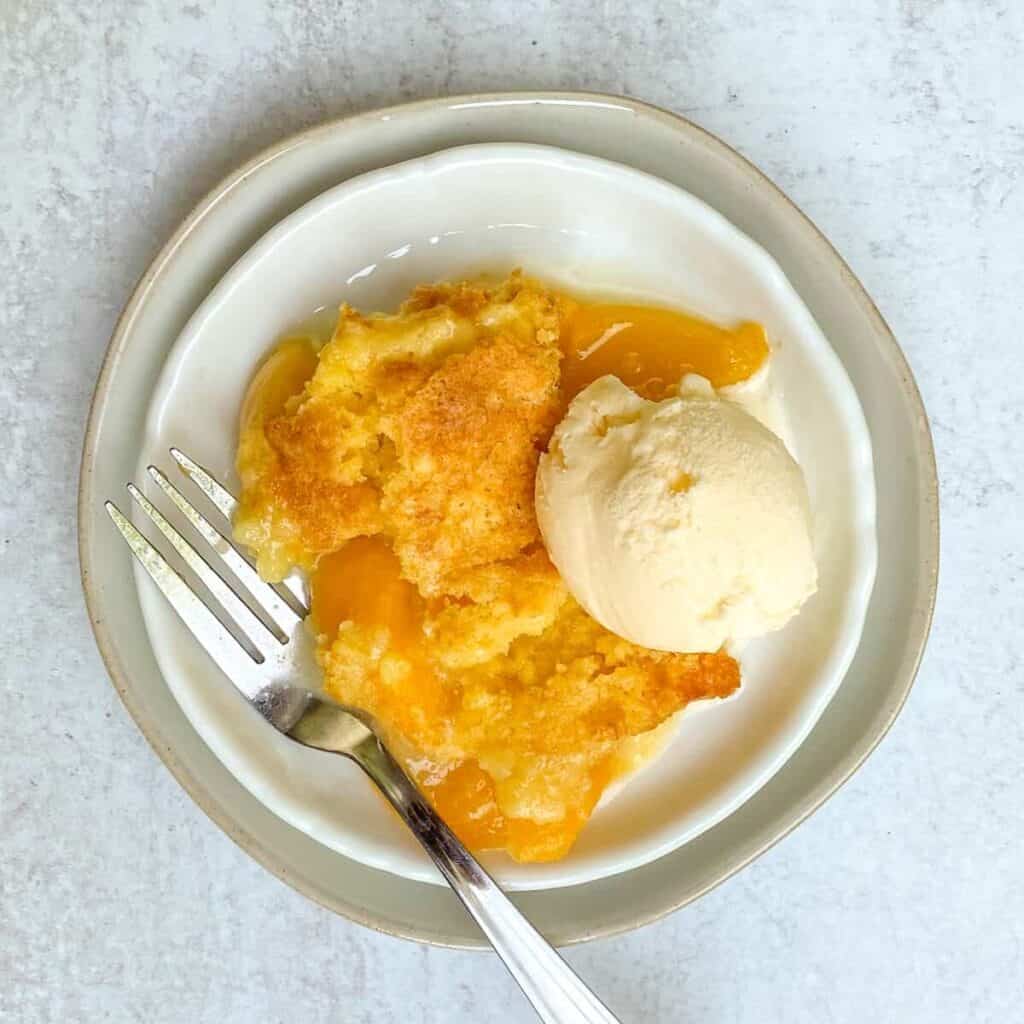 Peach Cobbler with Cake Mix served on a plate with ice cream.