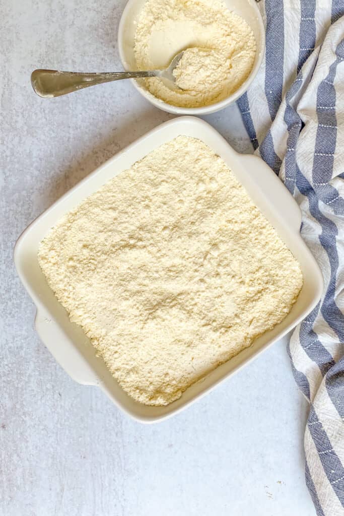 Yellow cake mix spread over canned peaches in a baking dish to make peach cobbler.