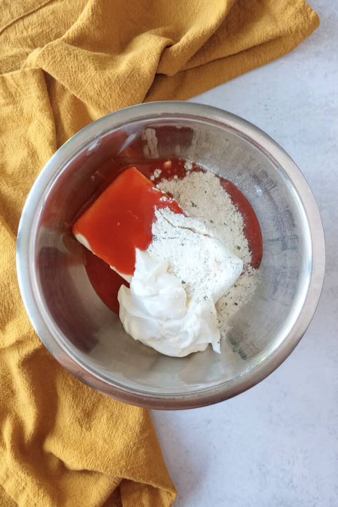 Cream cheese, sour, cream, dry ranch mix, and Franks red hot in a mixing bowl ready to be mixed up.