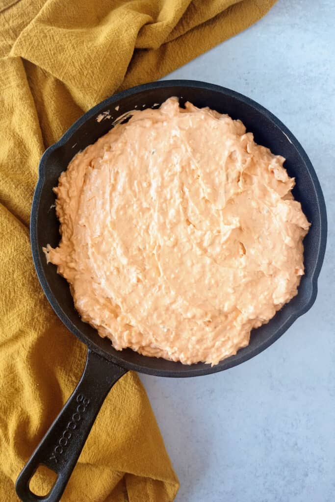 Top chicken dip with shredded cheese.