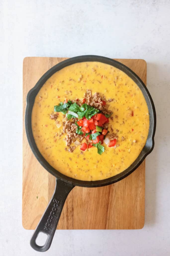 Velveeta queso dip on a cutting board in a black skillet ready to serve.