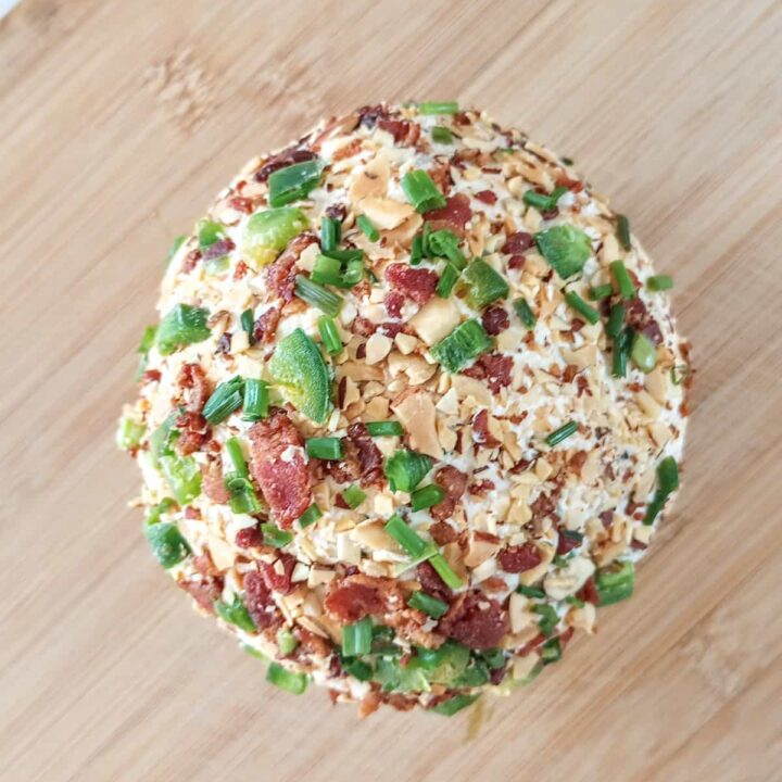 Jalapeno popper cheese ball arranged on a light brown chopping board.