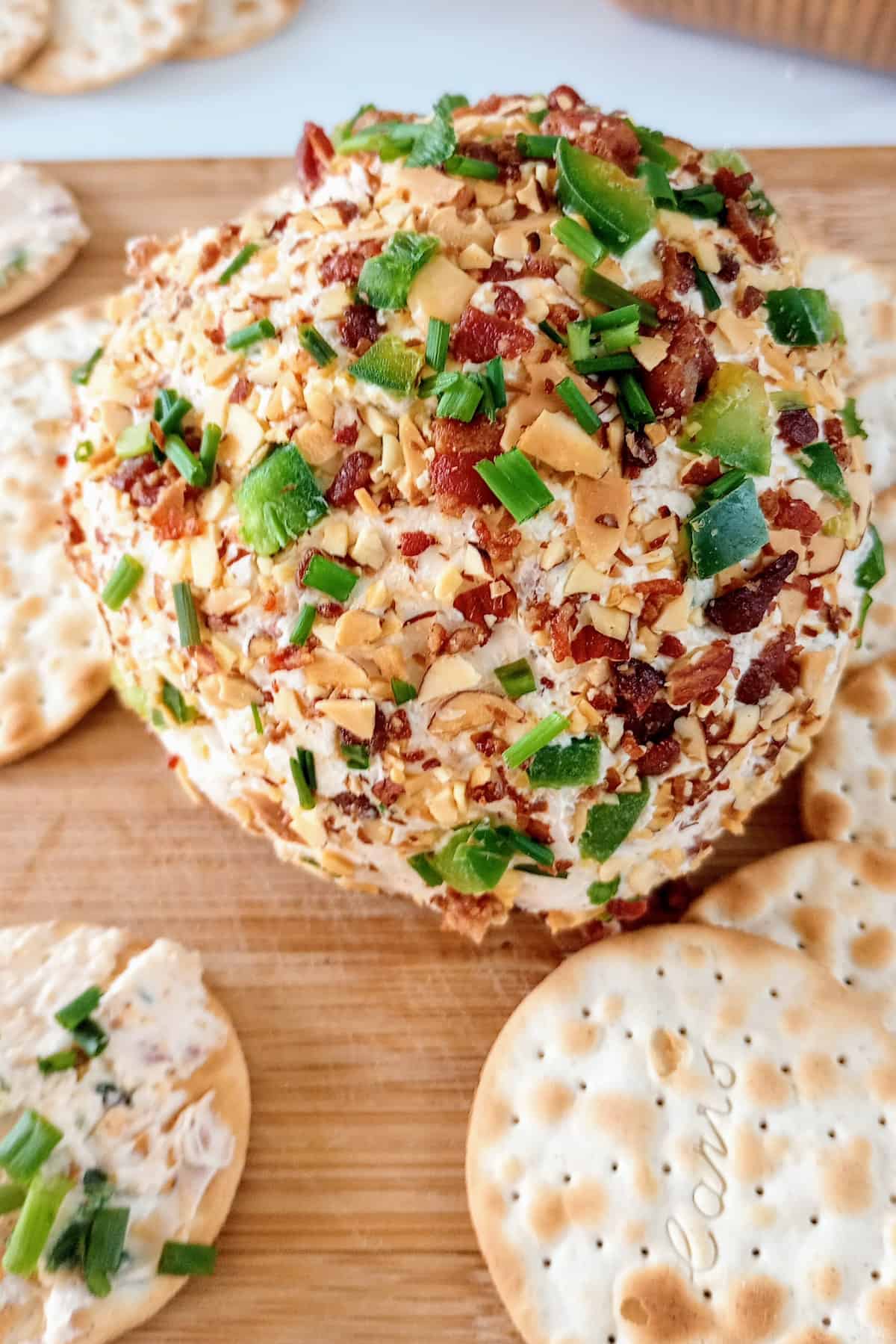 Jalapeno popper cheese ball next to crackers. Ready to eat.