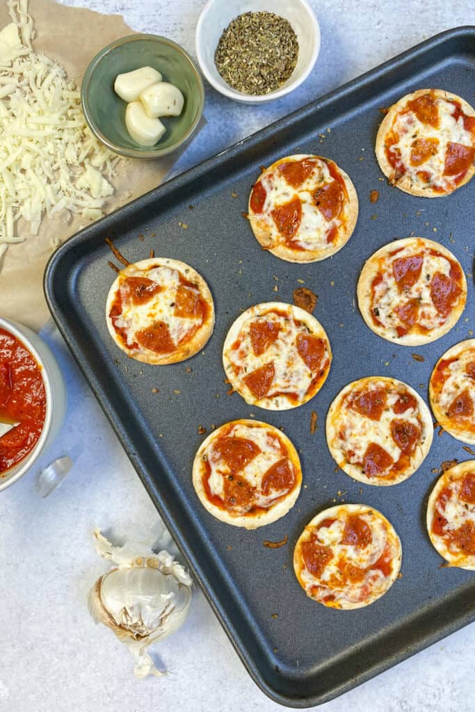 A baking tray with mini tortilla pizzas just out of the oven.