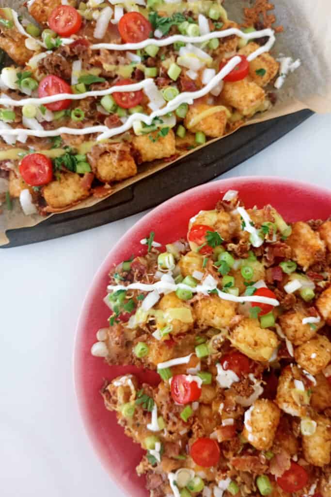 Tachos nachos on a red plate next to a baking sheet.