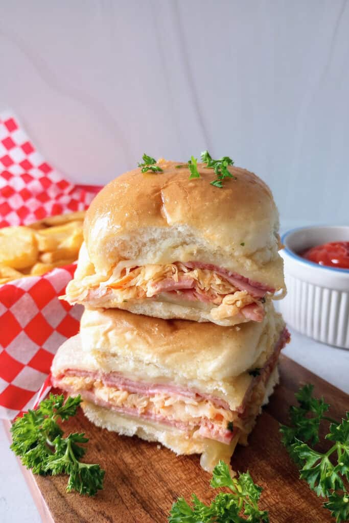 Mini sliders next to ketchup and a basket of french fries. 