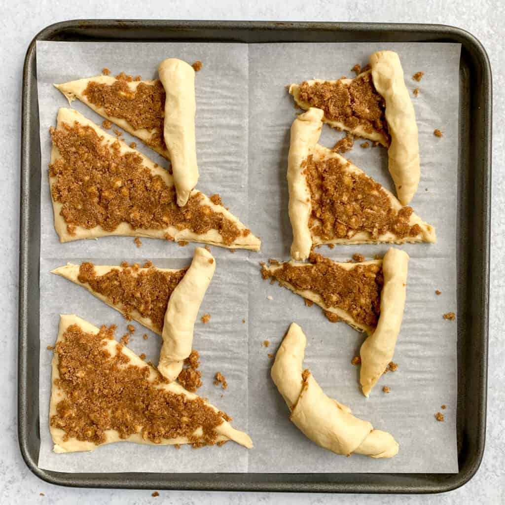 Rolling up dessert crescent rolls on baking sheet, showing that you start rolling at the wide end of crescent.