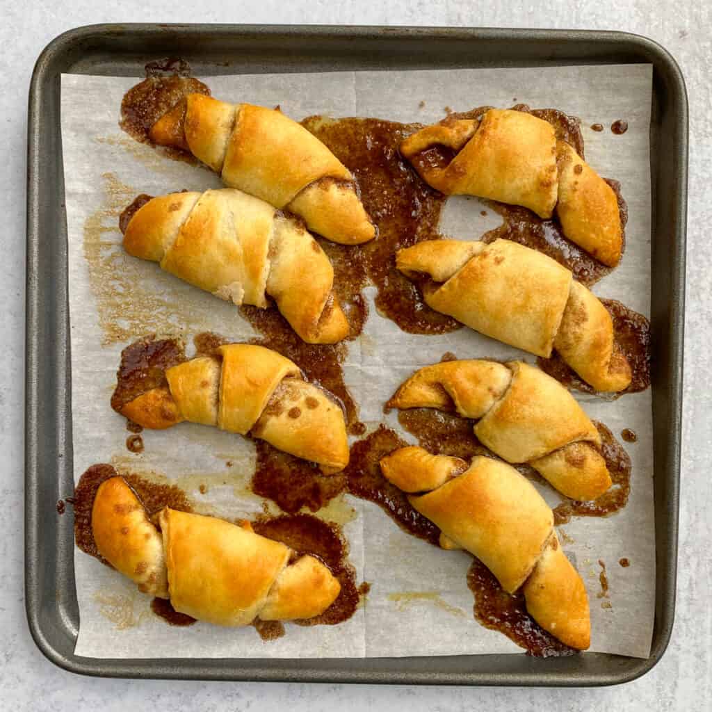 Baking sheet with light golden brown crescent rolls hot out of the oven.