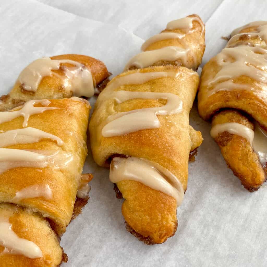 Close up picture of three dessert crescent rolls with sweet vanilla glaze drizzled over the tops.
