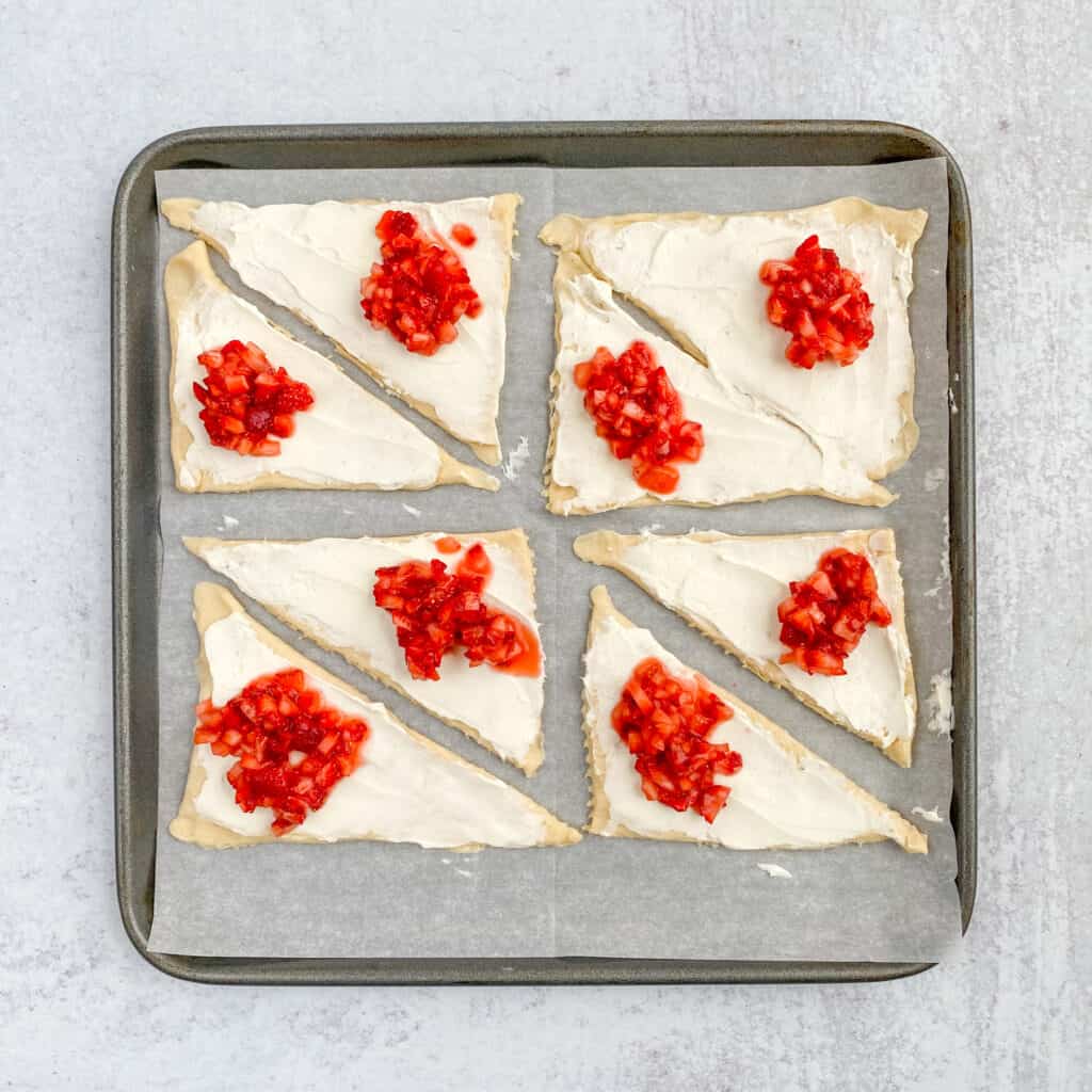 A scoop of strawberry filling on top of each cream cheese covered crescent.