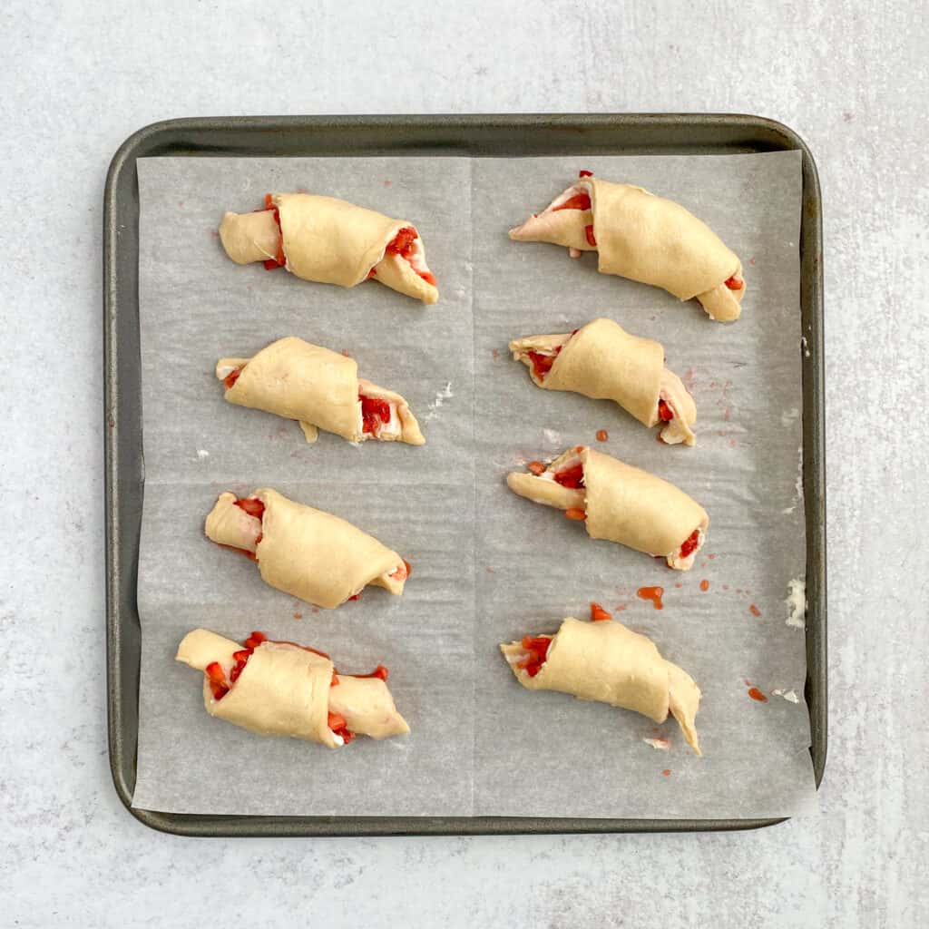 All the crescents rolled up and seam side down on the baking sheet.