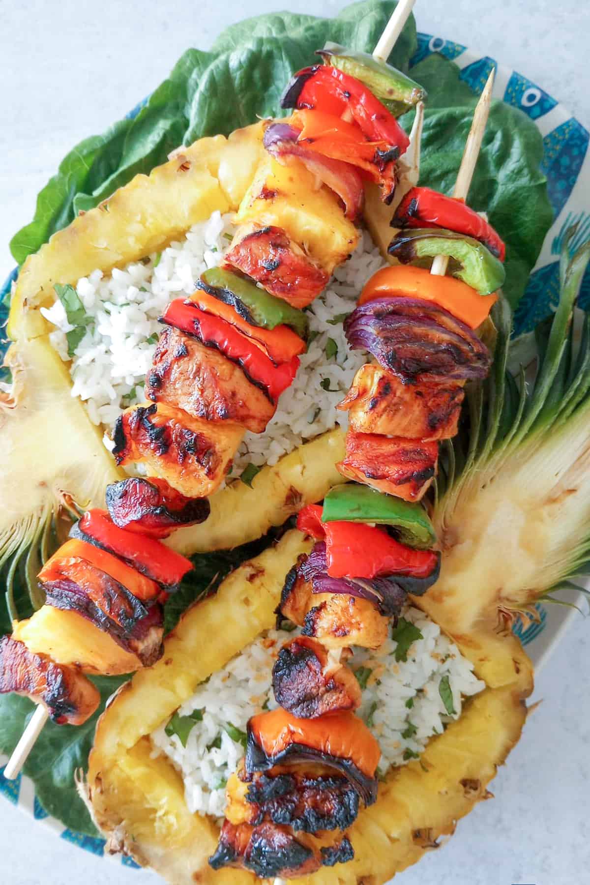 Easy Pineapple chicken kabobs arranged on top of fresh pineapple.