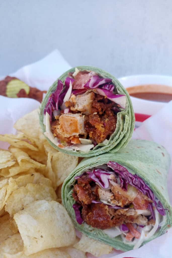 Nashville hot chicken wrap made with a Cajun remoulade sauce stuffed with crispy double-fried chicken, thinly sliced tomatoes, Cole slaw, and dill pickles.All wrapped in a large spinach wrap or large burrito wrap.  