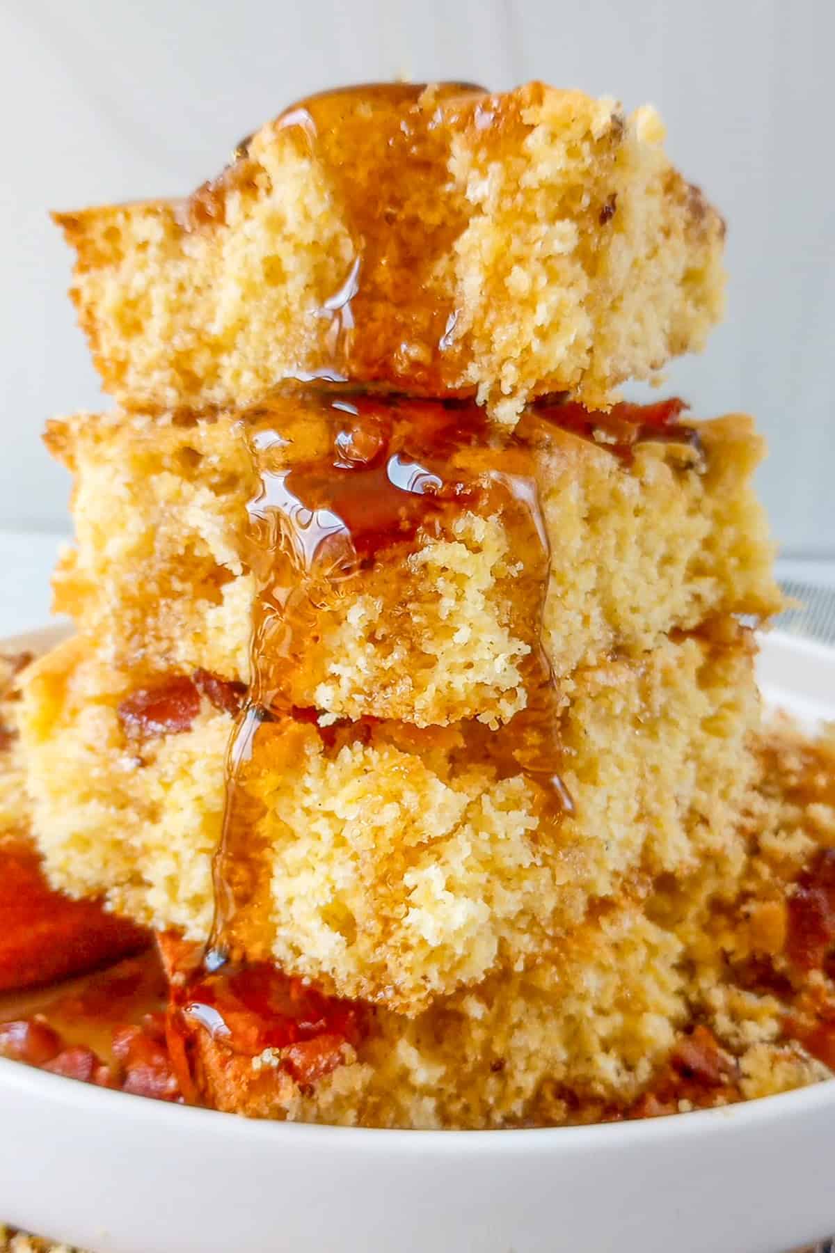 Maple bacon cornbread cut into squares and stacked on top of each other.