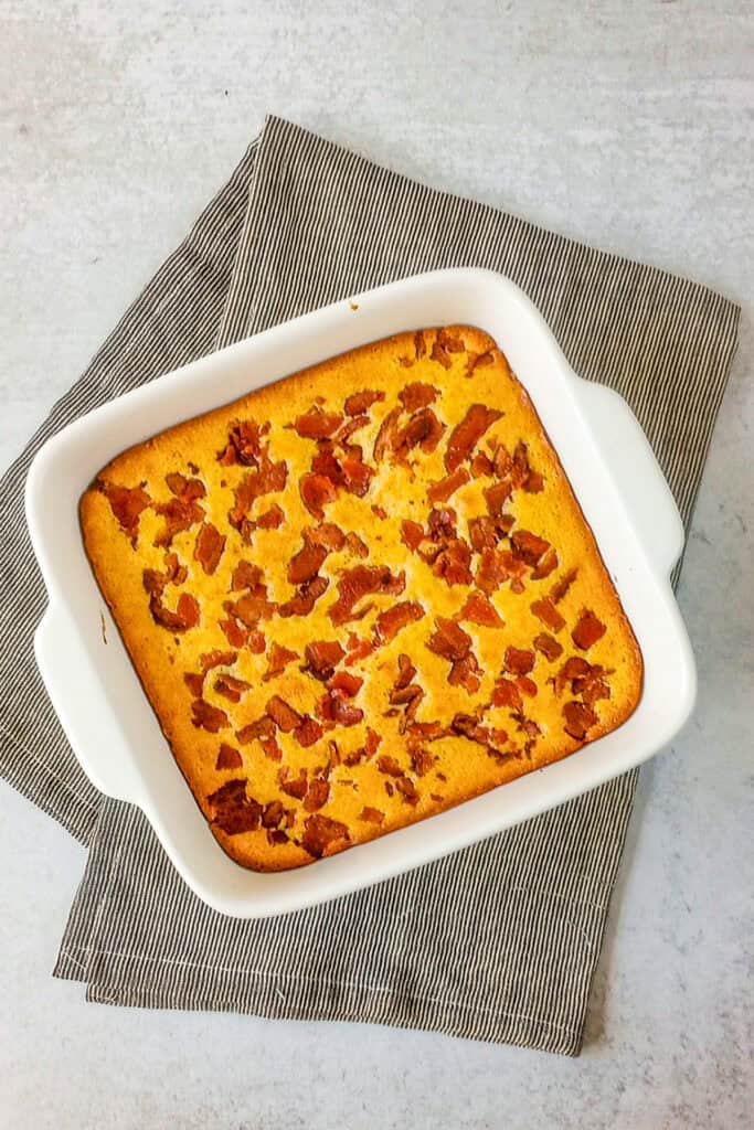 Cornbread in a pan with square baking dish on sitting on top of a towel.