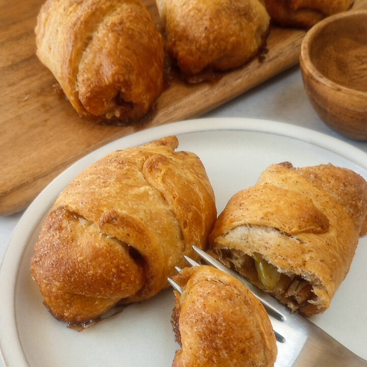 Up close picture of apple pie crescent rolls on a white plate.