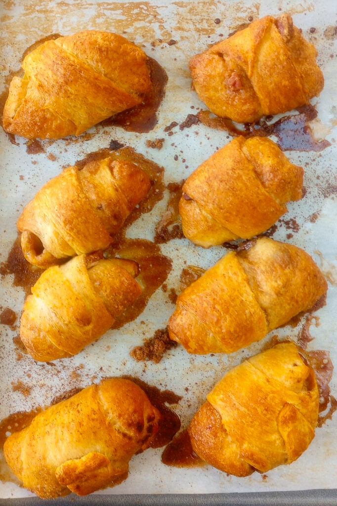 Overhead picture of apple pie bites on a baking sheet lined with white parchment paper.