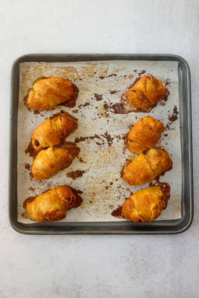 Overhead picture of apple pie bites fresh out of the oven on a baking sheet lined with parchment paper.