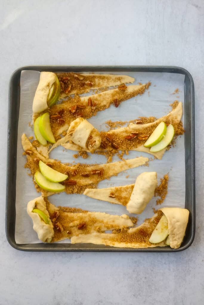 Overhead picture of apple pie bites showing how crescent rolls dough is rolled around the apples. 