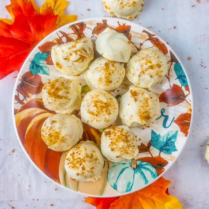 No bake pumpkin cheesecake balls on a fall plate with fall leaves on each corner.