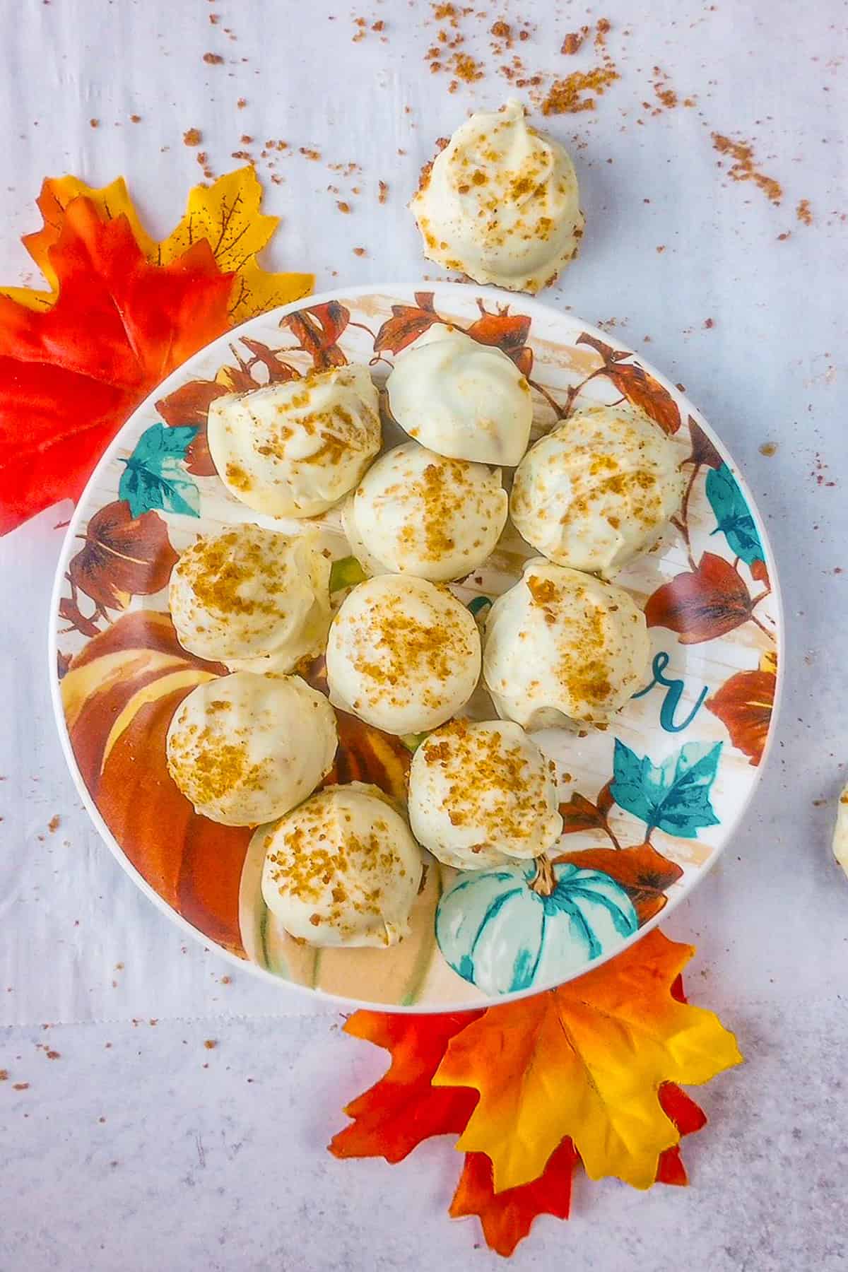 No bake pumpkin cheesecake balls on a fall plate with fall leaves on each corner.