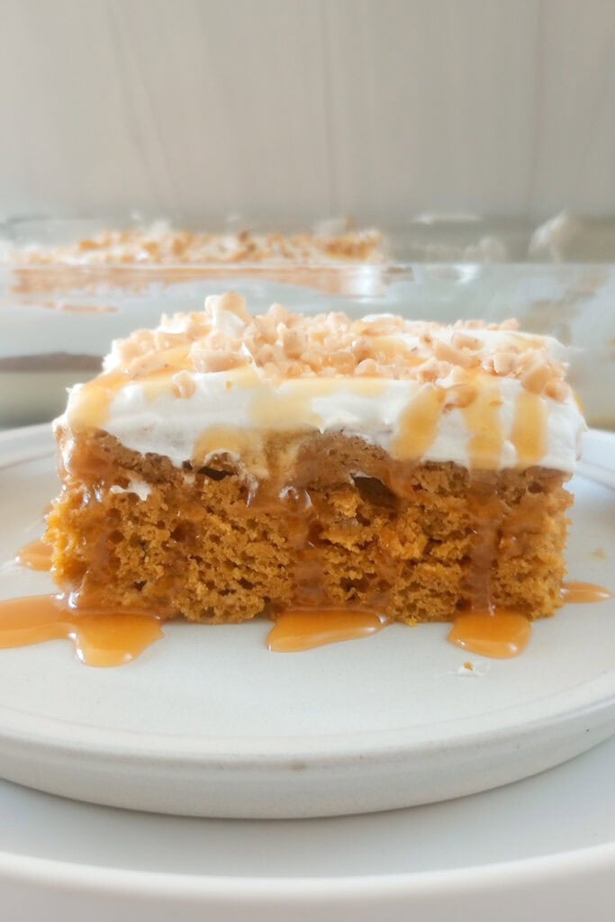 A slice of pumpkin poke cake dripping with caramel sauce.