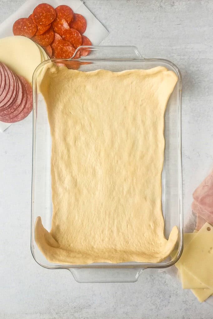 Overhead picture of bottom layer of crescent roll dough in a glass 9x13 inch pan. 