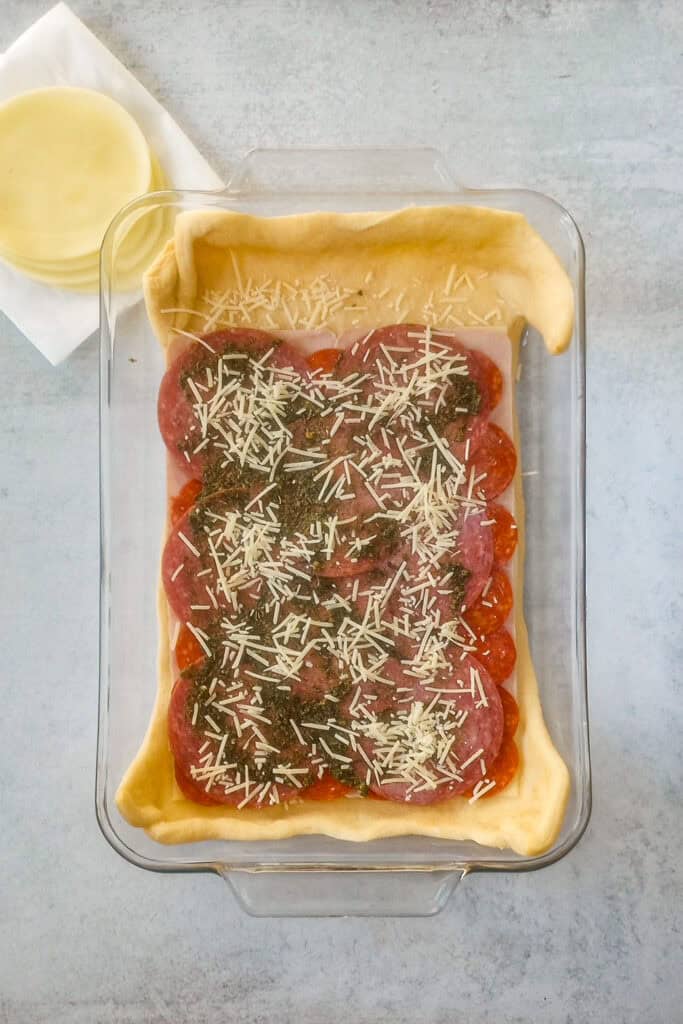 Over head picture of meat topped with pesto sauce and seasonings along with grated Parmesan cheese. 