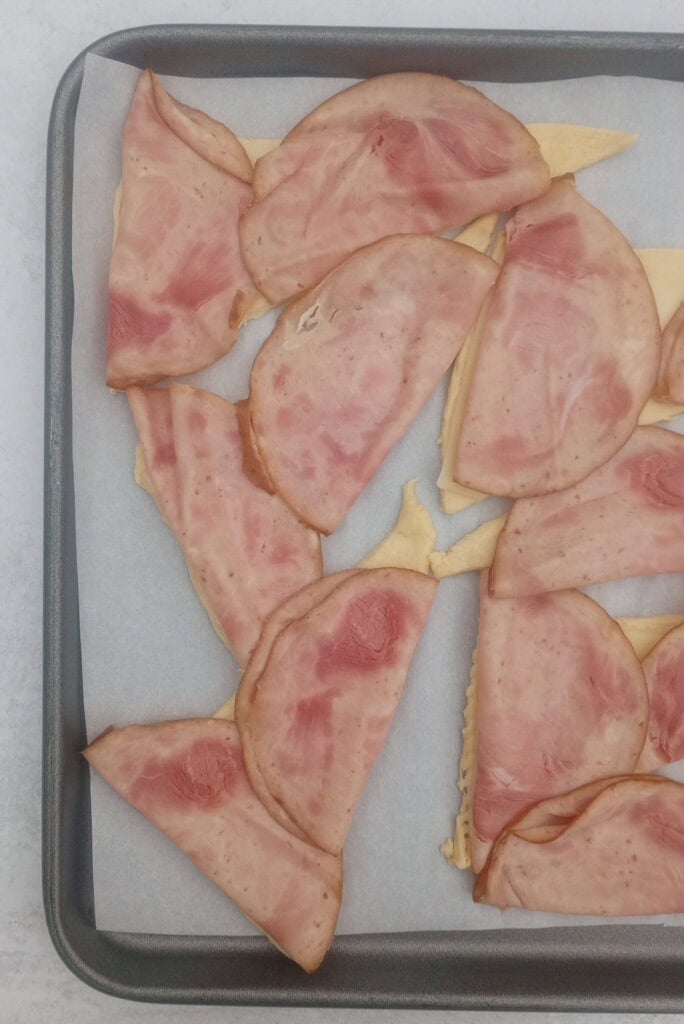 Overhead picture of sliced ham folded in half. Two slices are added to each crescent roll. 