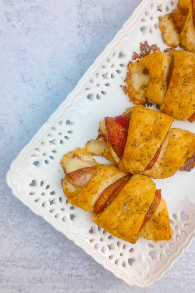 Overhead picture of hot ham and Swiss rolls on a white plate. 