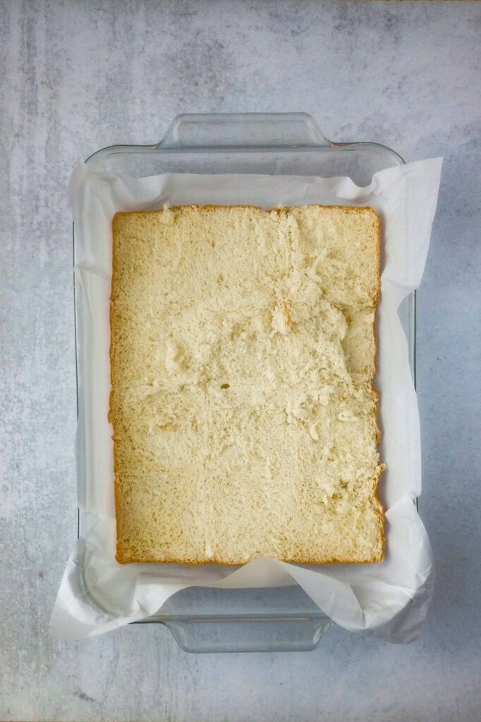 Overhead picture of Hawaiian rolls cut horizontally in a baking dish lined with white parchment paper. 