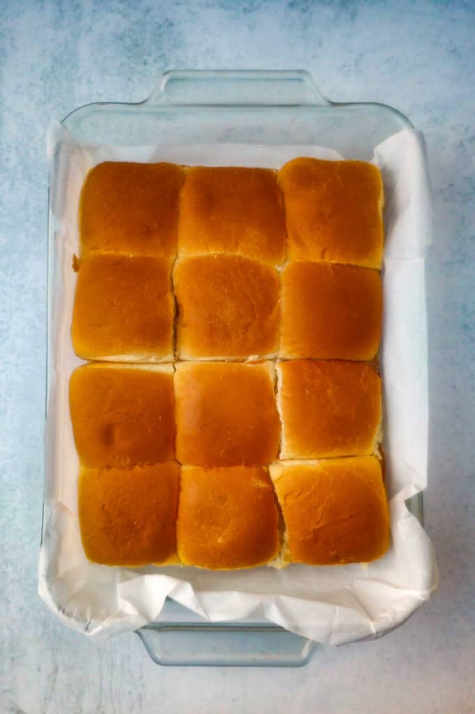 Overhead picture of Ham and cheese sliders topped with the top layer of buns. Ready to be baked in the oven. 