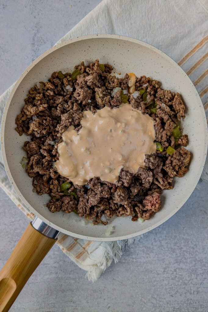 Overhead picture of cooked ground meat in a skillet with a glob of Big Mac sauce. 